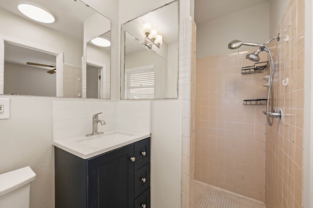 full bathroom with toilet, ceiling fan, tiled shower, and vanity