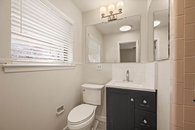bathroom with toilet, vanity, and tasteful backsplash