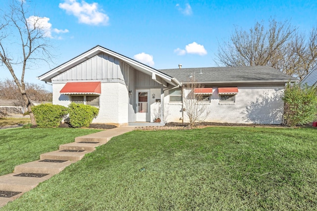 view of front of property with board and batten siding, a front yard, and brick siding