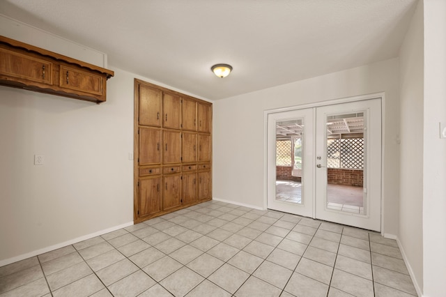 spare room with french doors, light tile patterned flooring, and baseboards