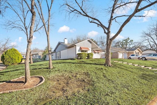 exterior space with an attached garage, a chimney, and a yard