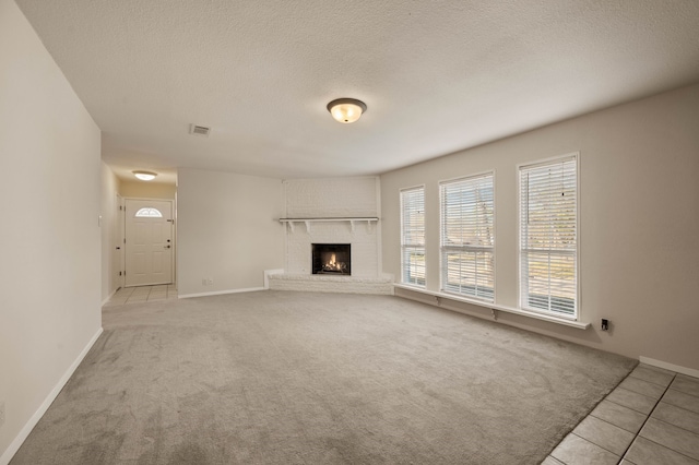 unfurnished living room featuring carpet flooring, a fireplace, visible vents, baseboards, and tile patterned flooring