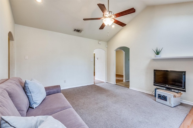 carpeted living area with arched walkways, visible vents, a ceiling fan, high vaulted ceiling, and baseboards