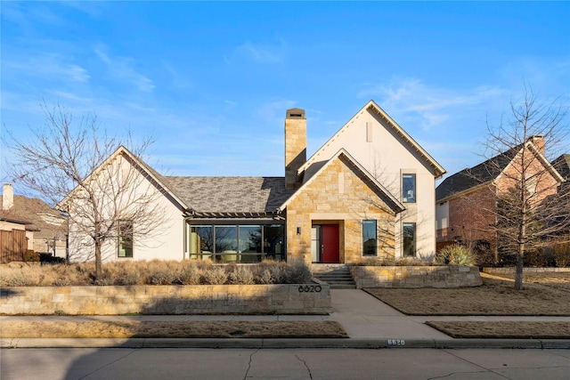 view of front of property with stone siding, a chimney, and stucco siding