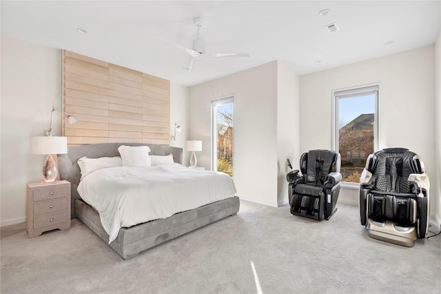 bedroom featuring a ceiling fan, light colored carpet, visible vents, and multiple windows