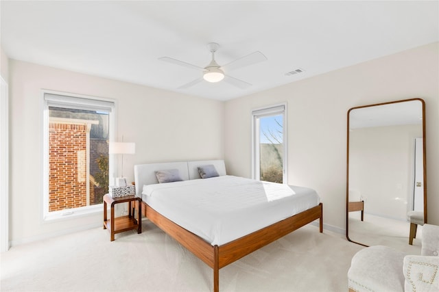 bedroom with baseboards, visible vents, a ceiling fan, and light colored carpet