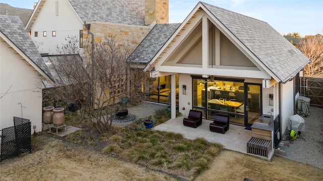 rear view of house with a patio, a chimney, fence, and stucco siding