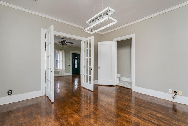 spare room with dark wood-type flooring, french doors, crown molding, and baseboards