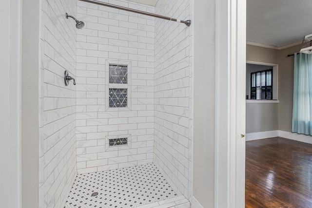 bathroom with a stall shower, crown molding, baseboards, and wood finished floors