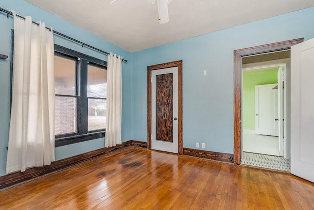 unfurnished room with ceiling fan, baseboards, and wood finished floors