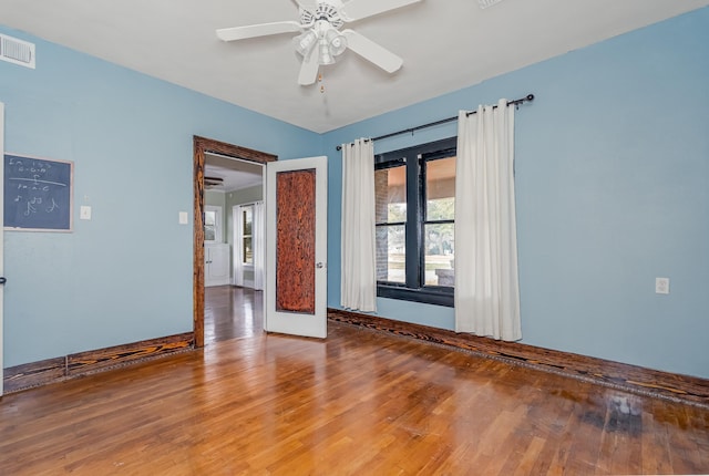 empty room with baseboards, wood finished floors, visible vents, and a ceiling fan