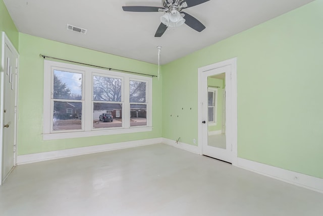 empty room with finished concrete floors, visible vents, baseboards, and a ceiling fan