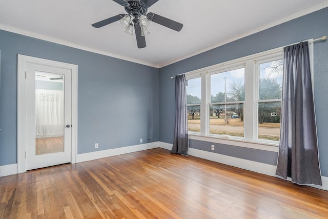 spare room with ornamental molding, wood finished floors, a ceiling fan, and baseboards