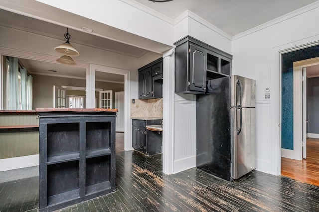 kitchen with a wainscoted wall, dark wood-style flooring, crown molding, and freestanding refrigerator