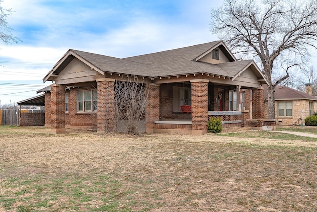 bungalow-style home with covered porch, brick siding, and a front lawn