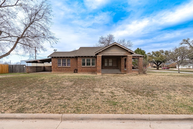 single story home featuring a carport, brick siding, a front lawn, and fence