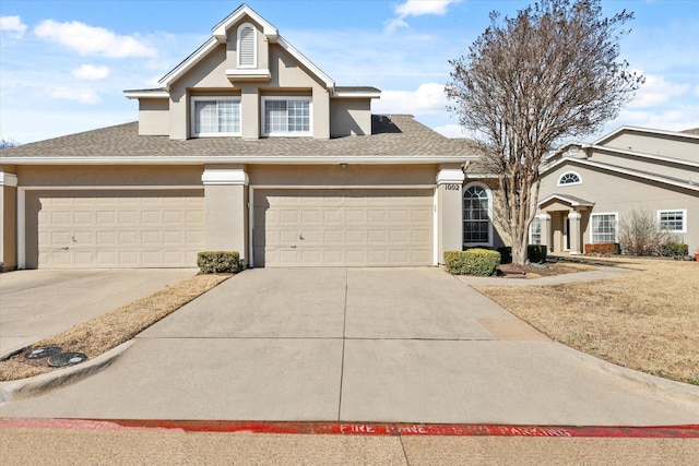 view of front of property with driveway, roof with shingles, and stucco siding