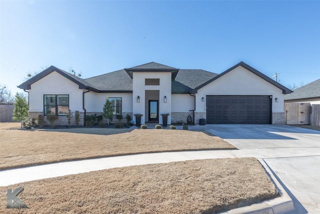 view of front of home with stucco siding, a shingled roof, an attached garage, fence, and driveway