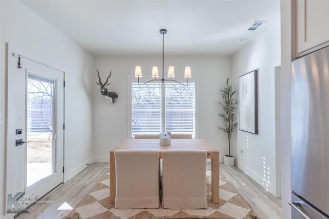 dining room featuring an inviting chandelier, baseboards, visible vents, and light wood finished floors