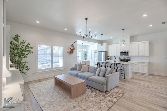 living area with light wood-type flooring, baseboards, a notable chandelier, and recessed lighting