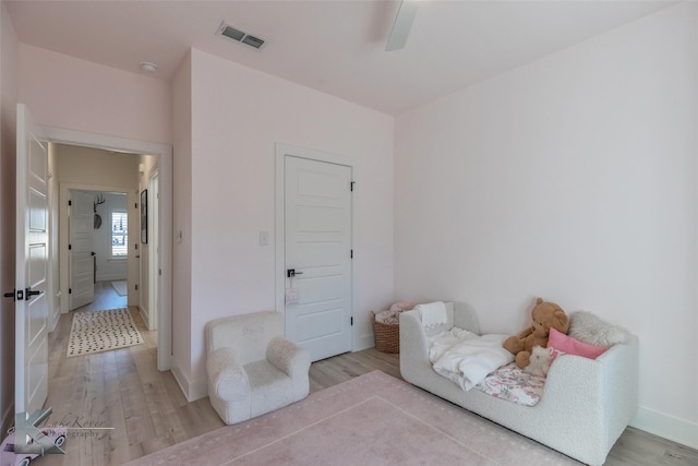 living area with light wood-style floors, visible vents, baseboards, and a ceiling fan