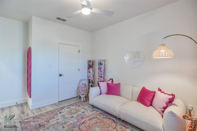 living area featuring light wood finished floors, ceiling fan, visible vents, and baseboards