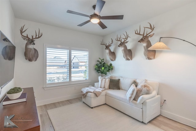 living area with light wood-type flooring, baseboards, and a ceiling fan