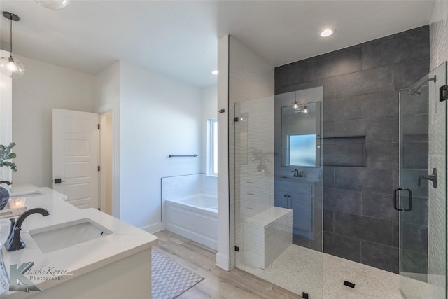 bathroom featuring a stall shower, baseboards, wood finished floors, a garden tub, and vanity