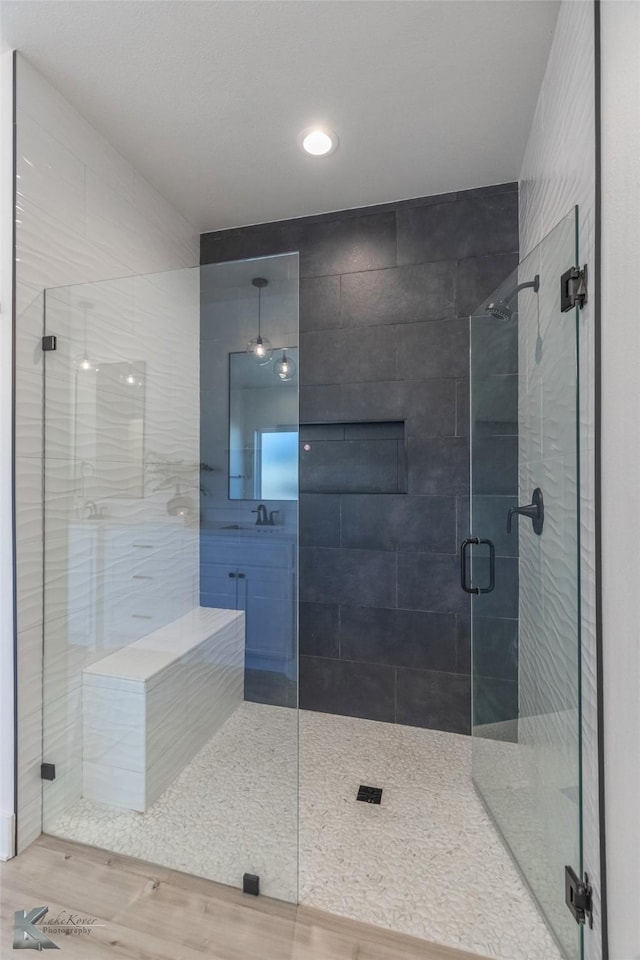 full bathroom featuring a sink, wood finished floors, and a shower stall