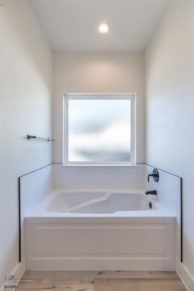 full bath featuring wood finished floors and a garden tub