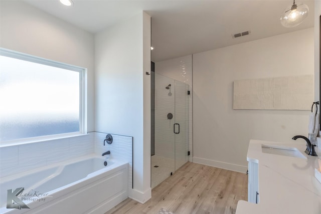 full bathroom with wood finished floors, vanity, visible vents, baseboards, and a stall shower