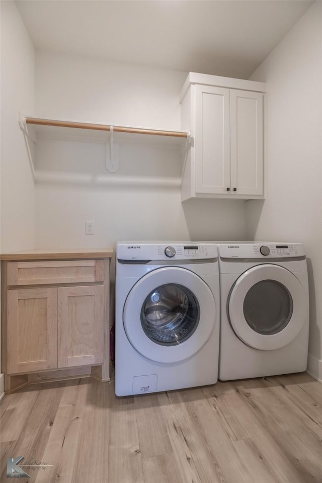 laundry room featuring light wood-type flooring, cabinet space, and washing machine and dryer