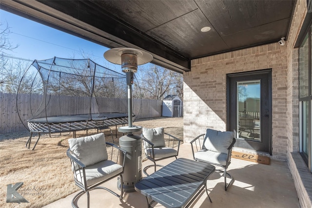 view of patio featuring a shed, a trampoline, and a fenced backyard