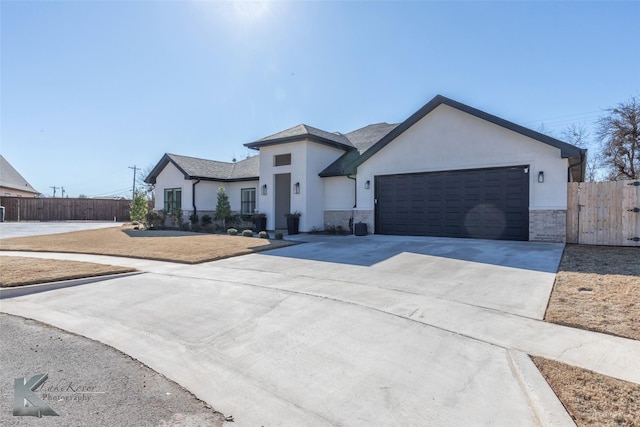 view of front facade featuring concrete driveway, fence, an attached garage, and stucco siding