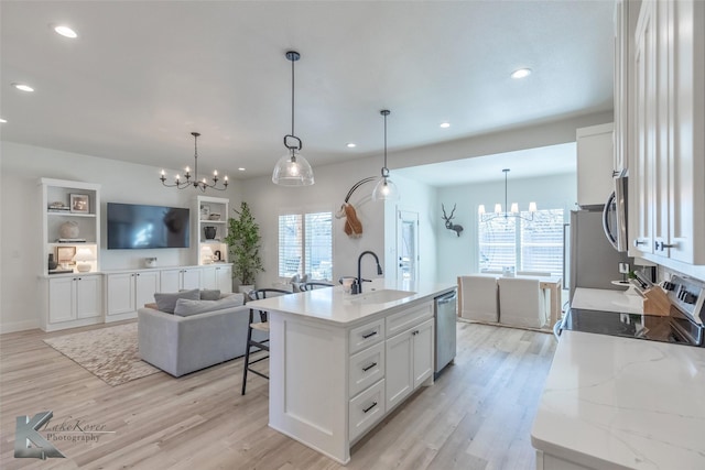 kitchen featuring a notable chandelier, open floor plan, white cabinetry, a sink, and an island with sink