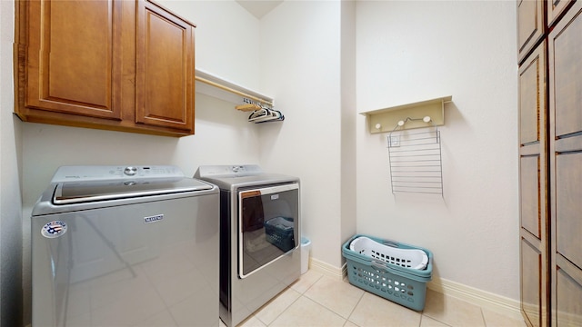 laundry room with cabinet space, light tile patterned floors, baseboards, and washer and dryer