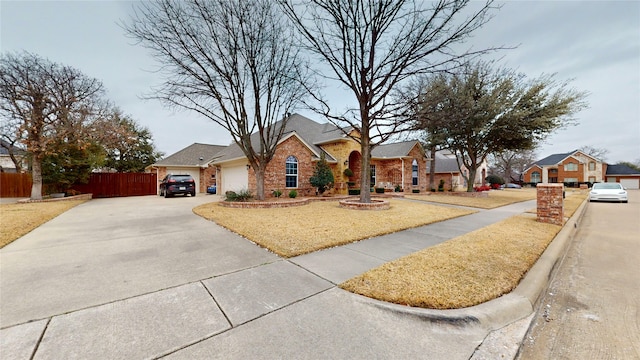 view of front of property with brick siding, concrete driveway, fence, a residential view, and a front lawn