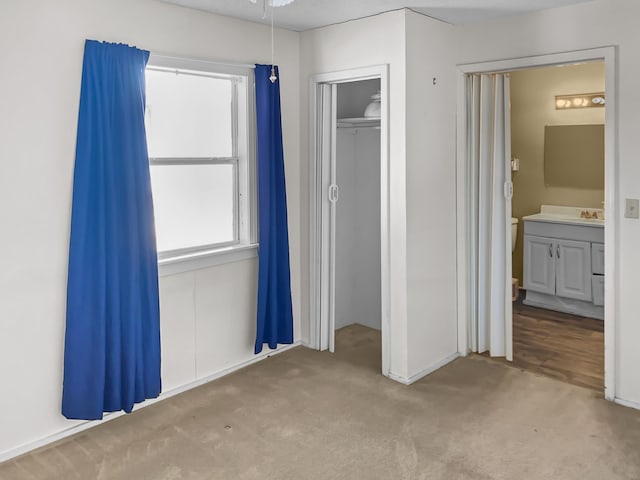 unfurnished bedroom with a closet, carpet flooring, and connected bathroom