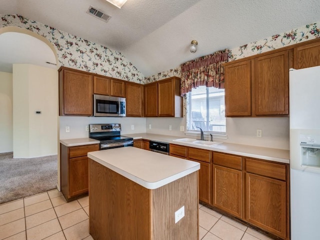 kitchen with brown cabinetry, visible vents, lofted ceiling, a sink, and stainless steel appliances