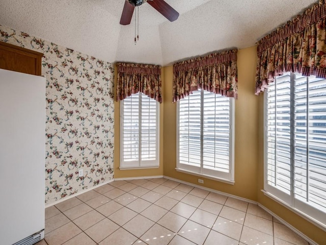 unfurnished room with a textured ceiling, wallpapered walls, ceiling fan, and vaulted ceiling