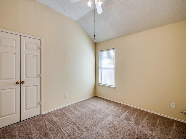 unfurnished room with baseboards, ceiling fan, vaulted ceiling, carpet flooring, and a textured ceiling