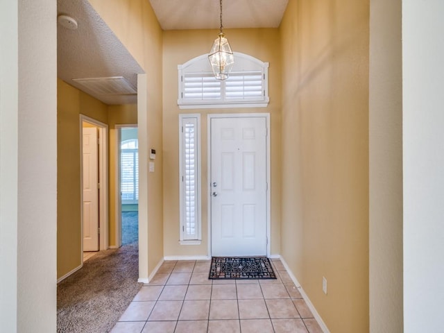 foyer featuring visible vents, a notable chandelier, light tile patterned flooring, and baseboards