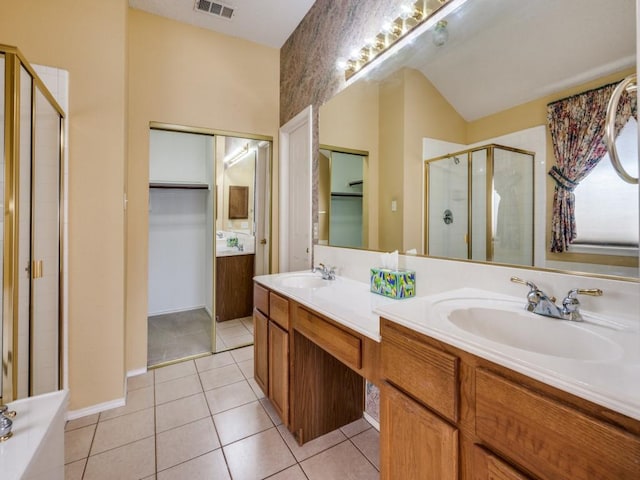 bathroom with tile patterned flooring, a shower stall, a walk in closet, and a sink