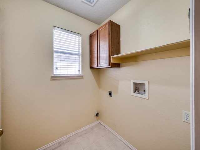 laundry area with electric dryer hookup, washer hookup, a textured ceiling, cabinet space, and baseboards