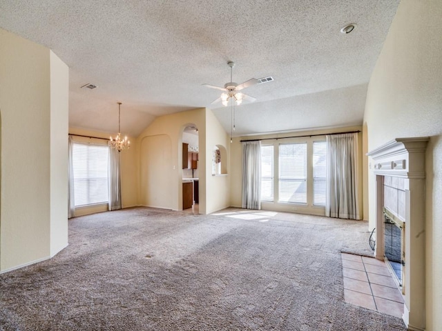 unfurnished living room featuring visible vents, a tiled fireplace, ceiling fan with notable chandelier, carpet, and vaulted ceiling