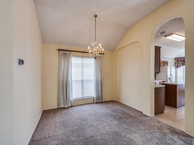 empty room featuring lofted ceiling, visible vents, a chandelier, and light carpet