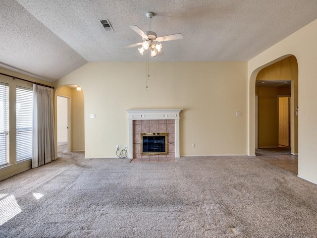 unfurnished living room with carpet, arched walkways, and a tile fireplace