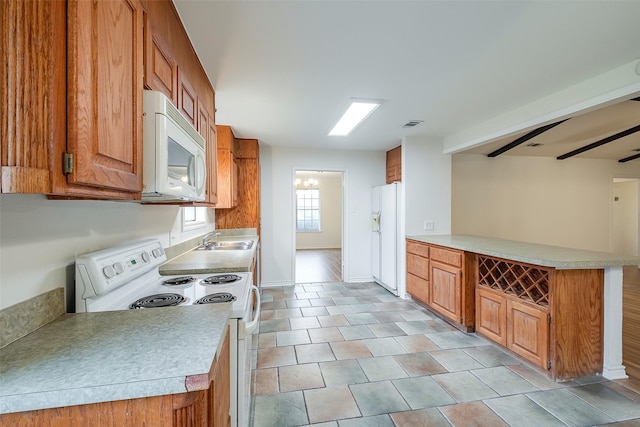 kitchen with brown cabinets, light countertops, a ceiling fan, a sink, and white appliances