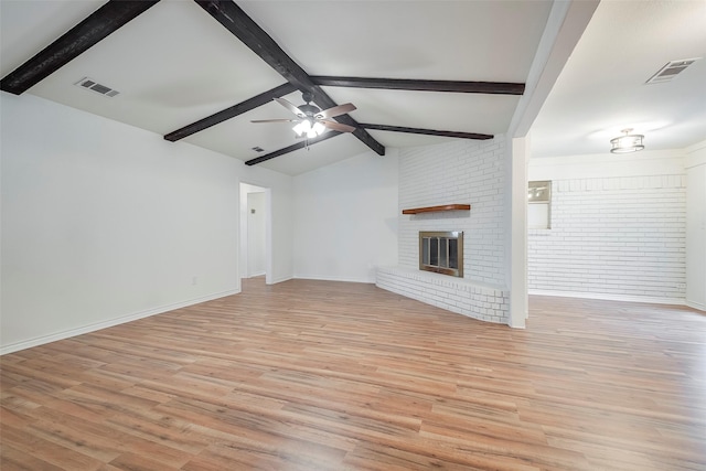 unfurnished living room featuring a brick fireplace, visible vents, vaulted ceiling with beams, and light wood-style flooring