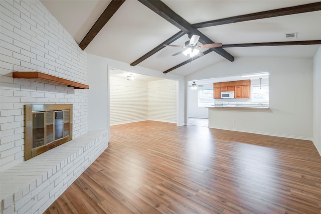 unfurnished living room featuring a fireplace, light wood finished floors, visible vents, lofted ceiling with beams, and ceiling fan